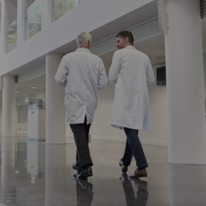 Zwei Ärzte laufen diskutierend über breiten Flur mit Hochglanzboden